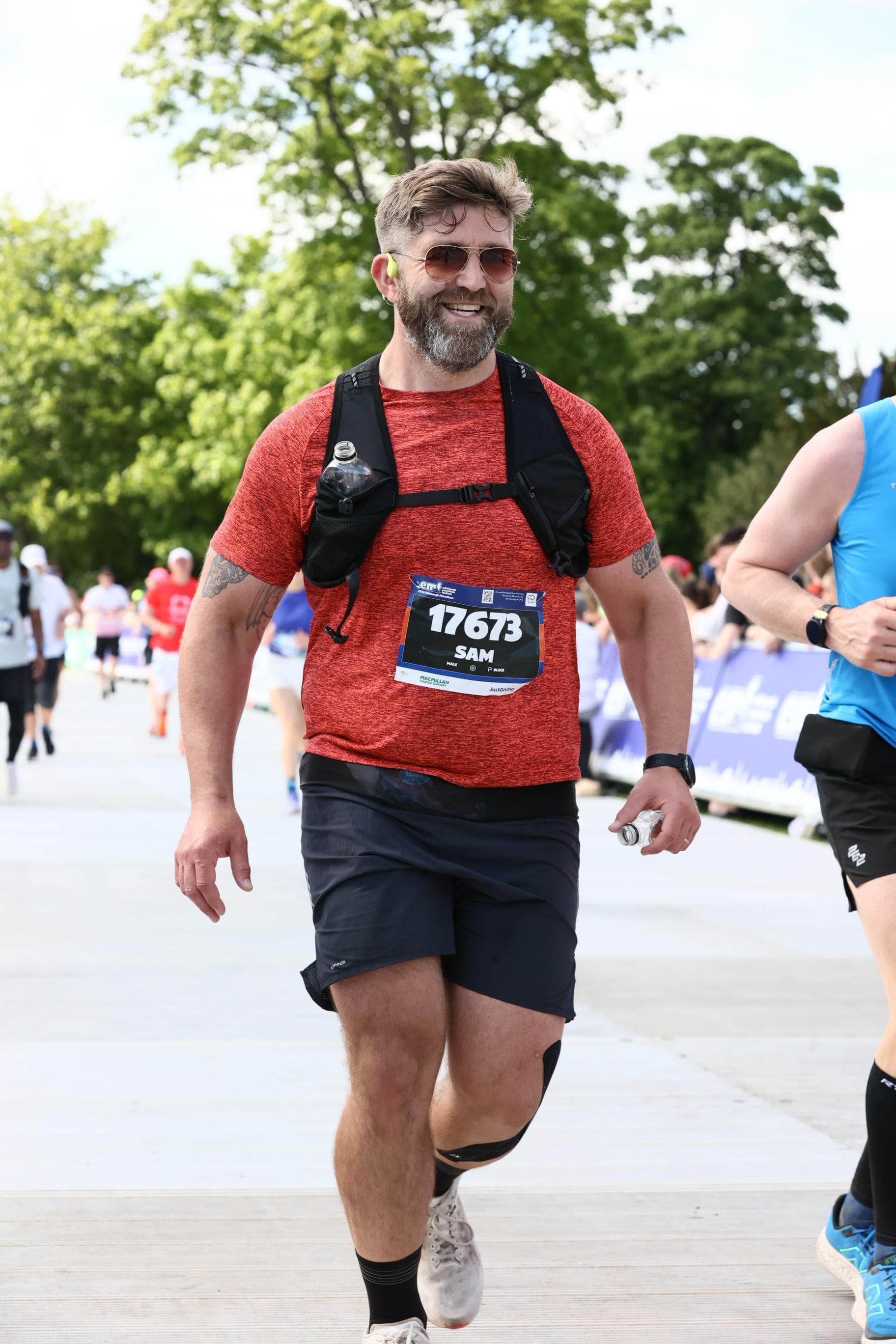 Sam running, wearing a race number at a marathon